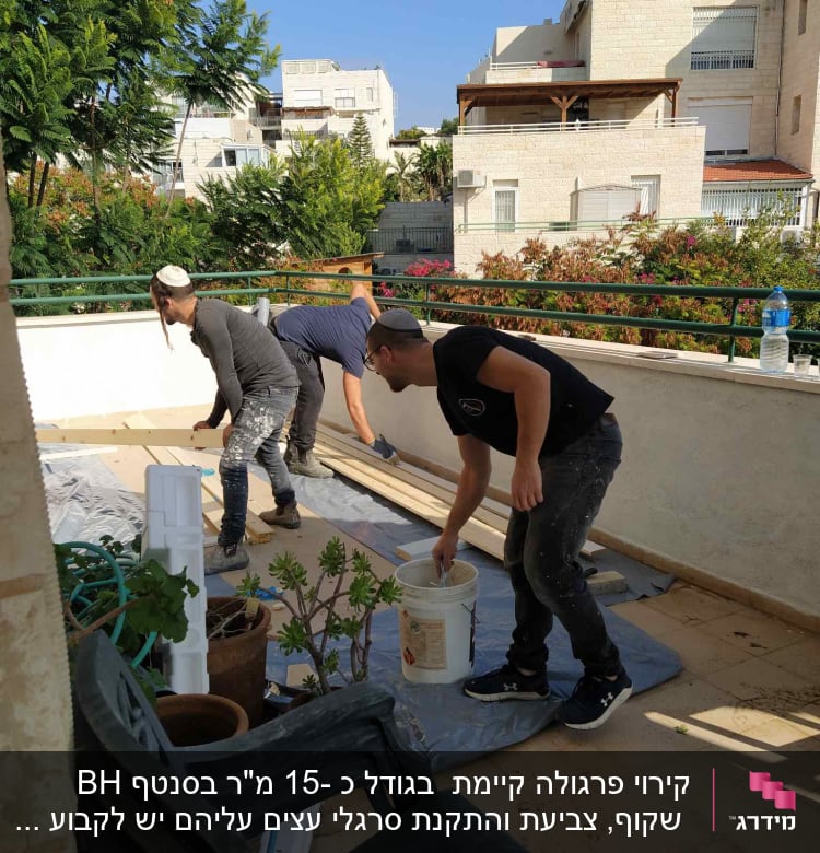 הצוות צובע בצבע של הפרגולה,ומכין את מרישי העץ להתקנה .